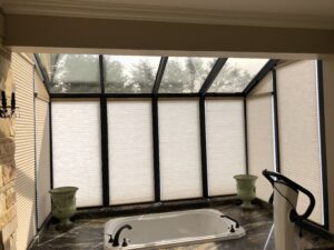 Motorized honeycomb shades on angled sunroom windows under a glass roof, Sevierville TN