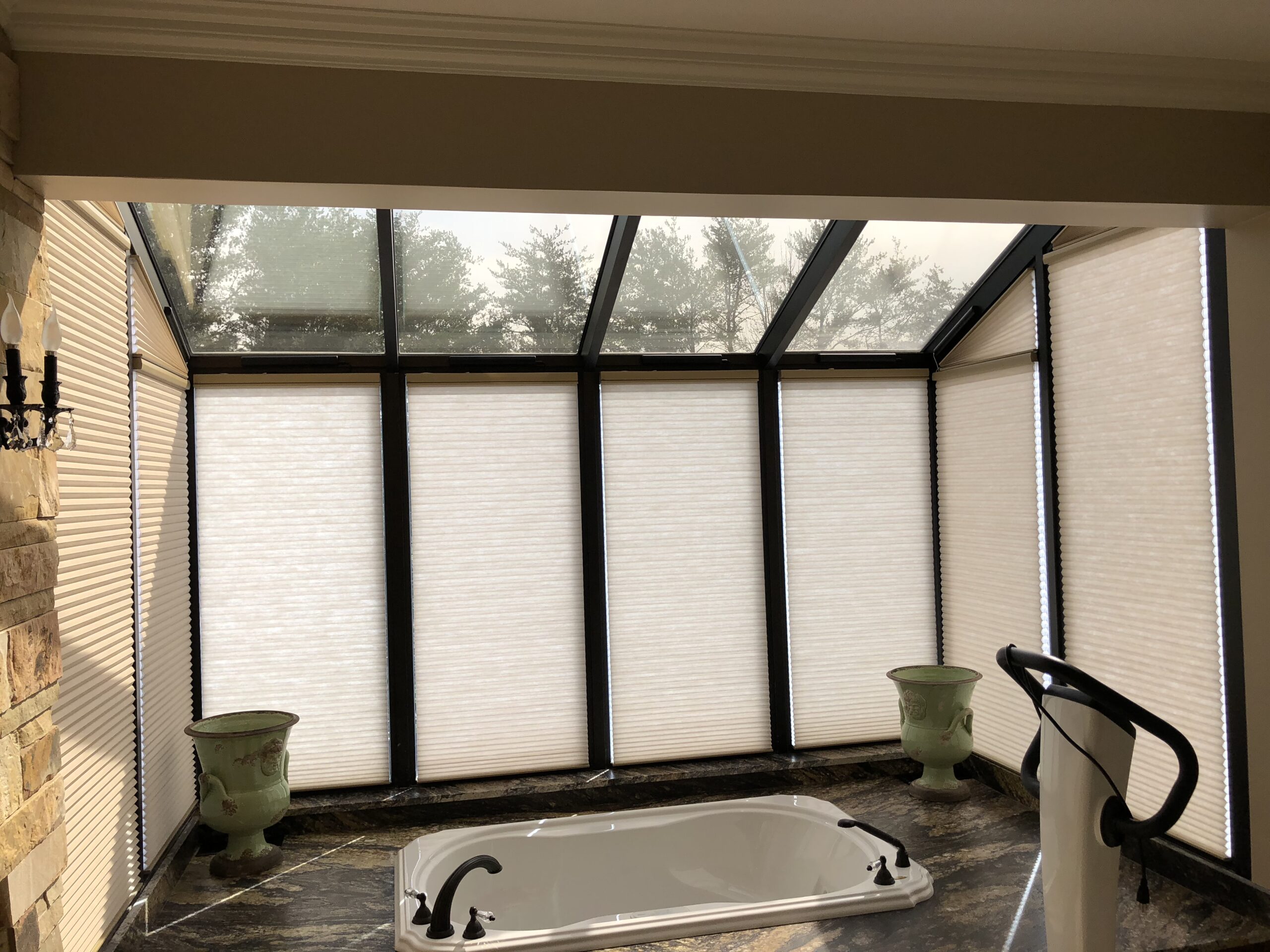 Motorized honeycomb shades on angled sunroom windows under a glass roof, Sevierville TN